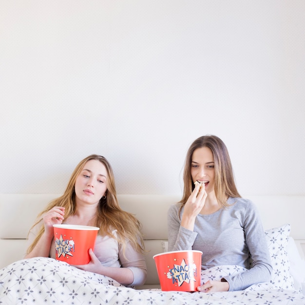 Mujeres comiendo palomitas de maíz en la cama