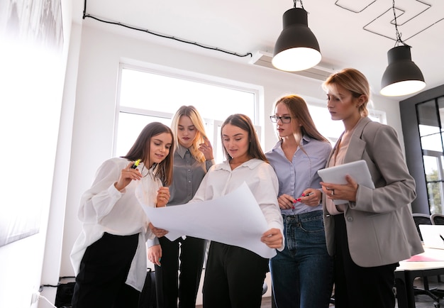 Mujeres corporativas de ángulo bajo que controlan planes