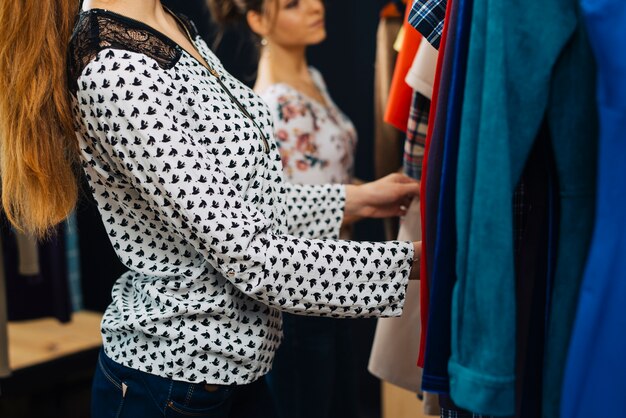 Mujeres de cultivo que eligen la ropa en la tienda