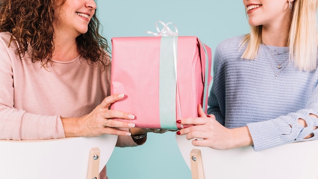 Mujeres de cultivos con caja de regalo en sillas