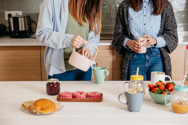 Foto gratuita mujeres de cultivos vertiendo té para el desayuno