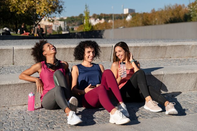 Mujeres deportivas de tiro completo sentados juntos