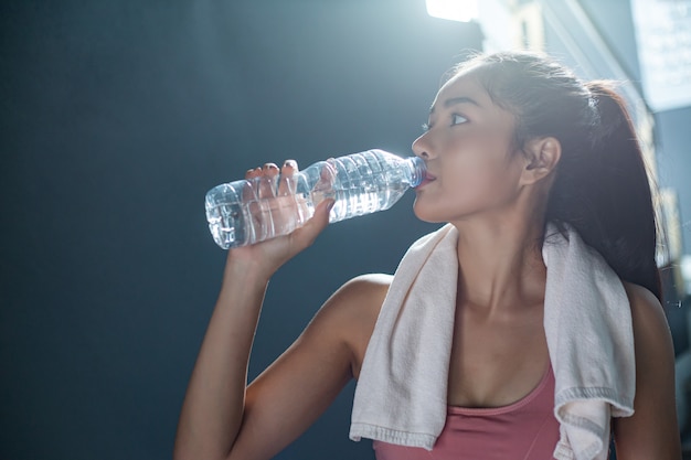 Las mujeres después del ejercicio beben agua de botellas y pañuelos en el gimnasio.
