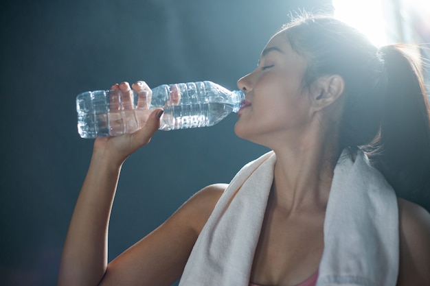 Las mujeres después del ejercicio beben agua de botellas y pañuelos en el gimnasio.