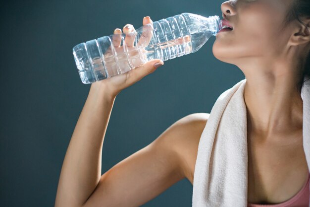 Las mujeres después del ejercicio beben agua de botellas y pañuelos en el gimnasio.