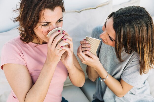 Mujeres disfrutando de bebidas calientes en el sofá