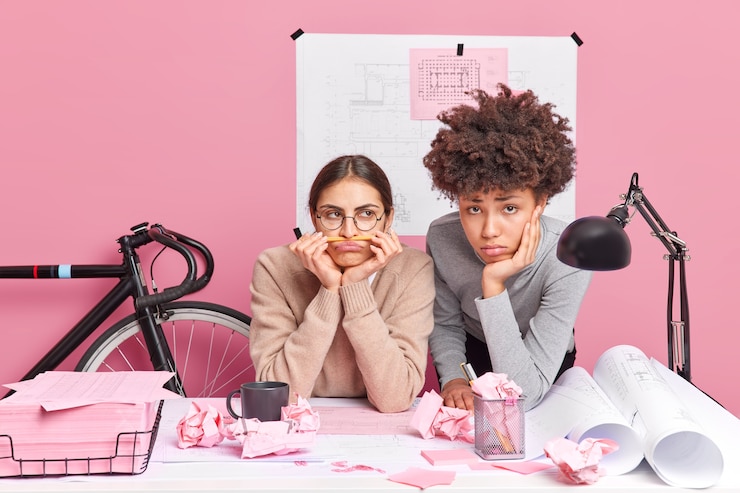 Foto gratuito mujeres diversas, aburridas y tristes, insatisfechas con el proceso de trabajo, tratan de encontrar una solución al problema. concepto de lluvia de ideas