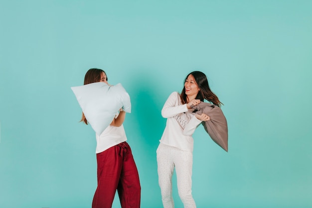 Foto gratuita mujeres divertidas que tienen pelea de almohadas