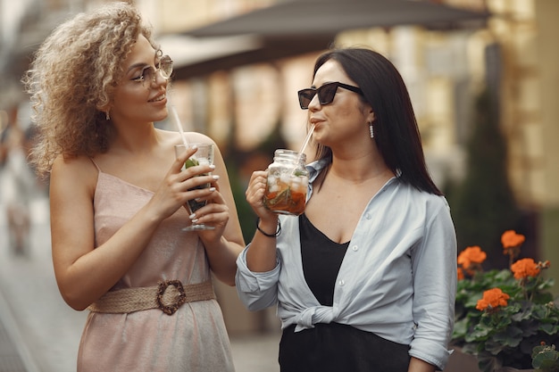 Mujeres elegantes bebe cócteles en una ciudad de verano