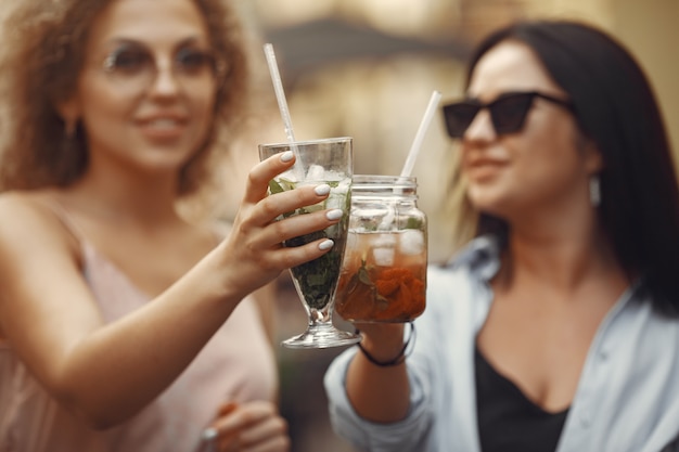 Mujeres elegantes bebe cócteles en una ciudad de verano