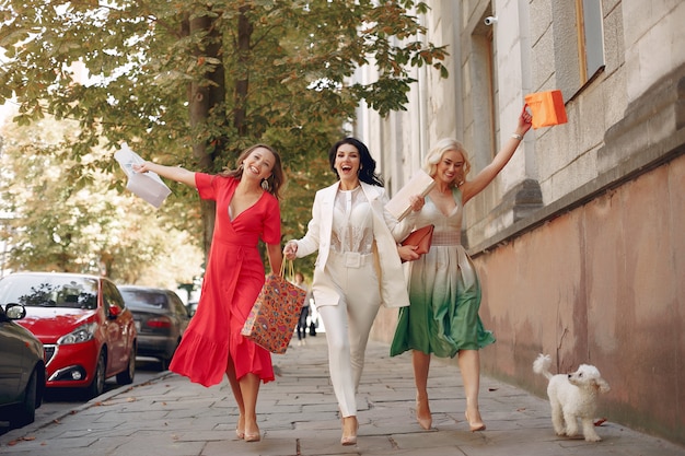 mujeres elegantes con bolsas de compras en una ciudad