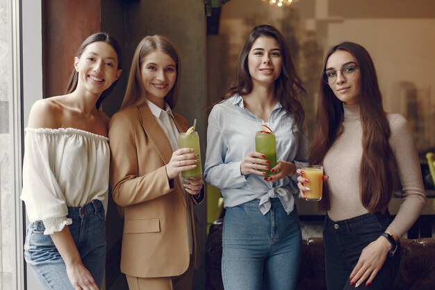 Mujeres elegantes de pie en un café y bebiendo un cóctel