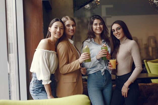 Mujeres elegantes de pie en un café y bebiendo un cóctel