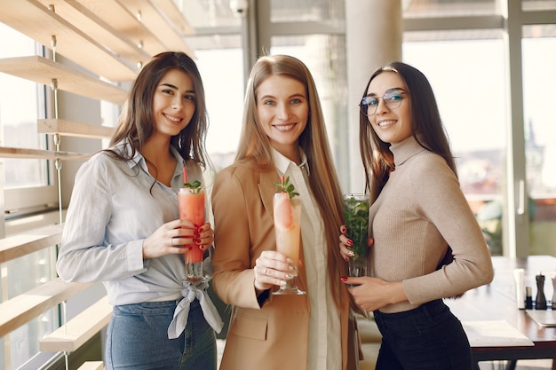 Mujeres elegantes de pie en un café y bebiendo un cóctel