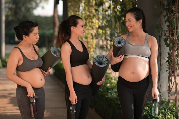 Mujeres embarazadas con colchonetas de yoga