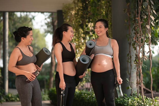 Mujeres embarazadas con colchonetas de yoga