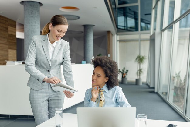 Mujeres empresarias felices revisando informes mientras trabajan en la oficina