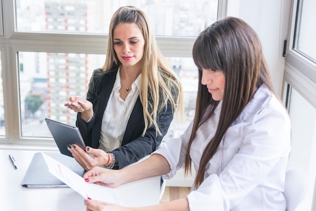 Foto gratuita mujeres empresarias jóvenes discutiendo el documento en la oficina