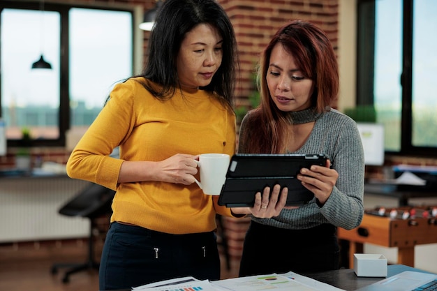 Mujeres empresarias que comparan las estadísticas de gestión de este año con el año pasado trabajando en la estrategia de la empresa para aumentar los ingresos. Equipo de marketing discutiendo ideas de asociación comercial en la oficina de inicio