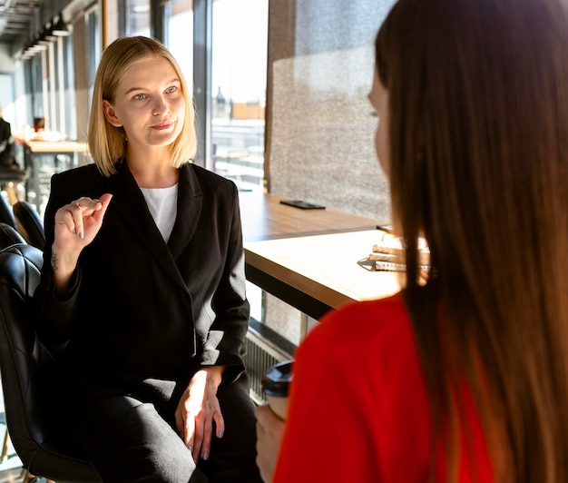 Mujeres empresarias que utilizan el lenguaje de señas en el trabajo para comunicarse entre sí