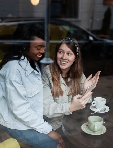 Mujeres encantadoras disfrutando de café junto a la ventana