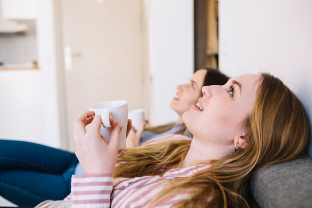 Mujeres encantadoras con tazas mirando hacia arriba