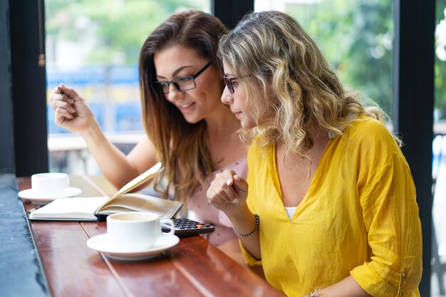 Mujeres enfocadas que beben el café y que trabajan en café