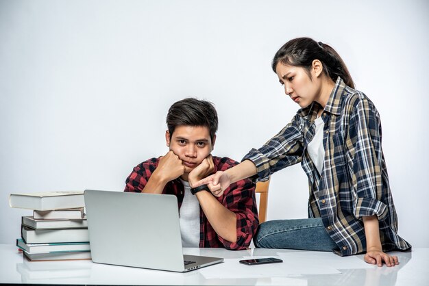 Las mujeres enseñan a los hombres cómo trabajar con computadoras portátiles.