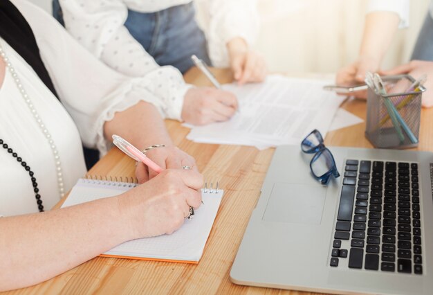 Mujeres escribiendo en cuadernos y computadoras portátiles