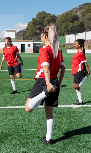 Mujeres estirando la pierna en el campo de fútbol