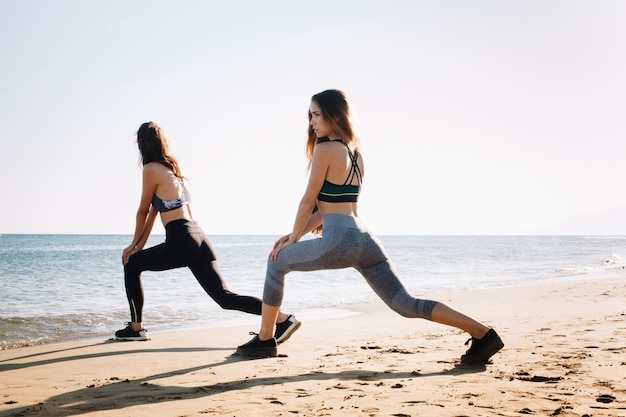 Foto gratuita mujeres estirando piernas por la playa