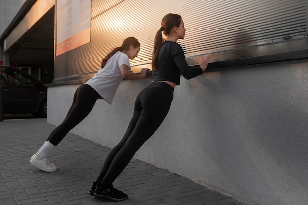 Foto gratuita mujeres estirándose juntas antes de hacer ejercicio al aire libre