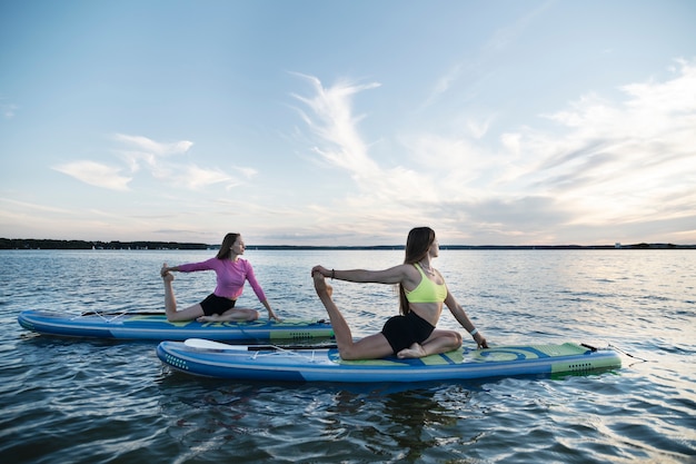 Mujeres estirándose en la vista lateral de paddleboard
