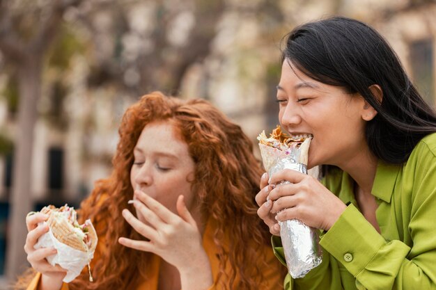 Mujeres felices comiendo juntos comida callejera