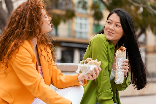 Foto gratuita mujeres felices comiendo juntos comida callejera