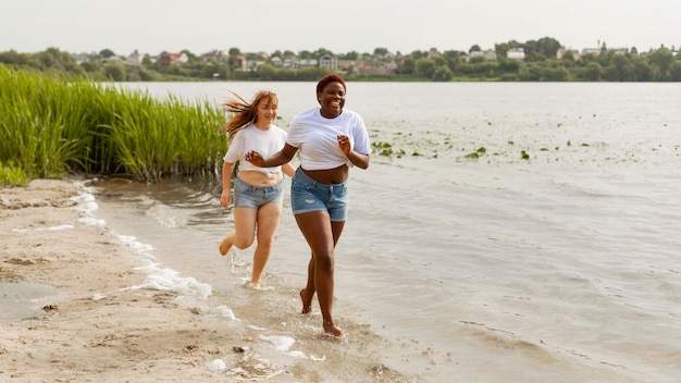 Mujeres felices corriendo juntos en la playa