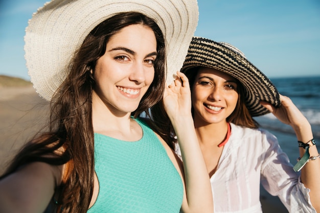 Mujeres felices haciendo selfie en la playa