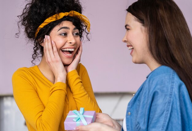 Mujeres felices sonrientes dándose regalos