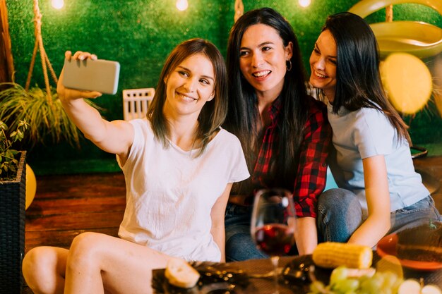 Mujeres felices tomando selfie en fiesta