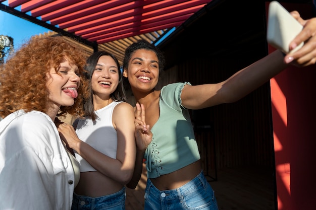 Mujeres felices tomando selfie tiro medio