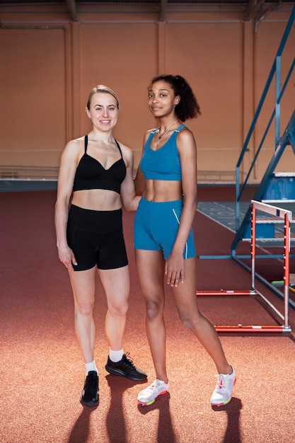 Foto gratuita mujeres en forma de tiro completo con equipo en el gimnasio