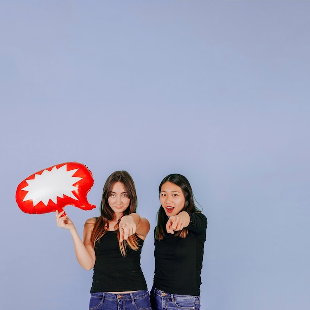 Foto gratuita mujeres con globo de discurso apuntando a la cámara