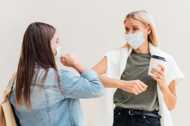 Mujeres haciendo codazos con distanciamiento social