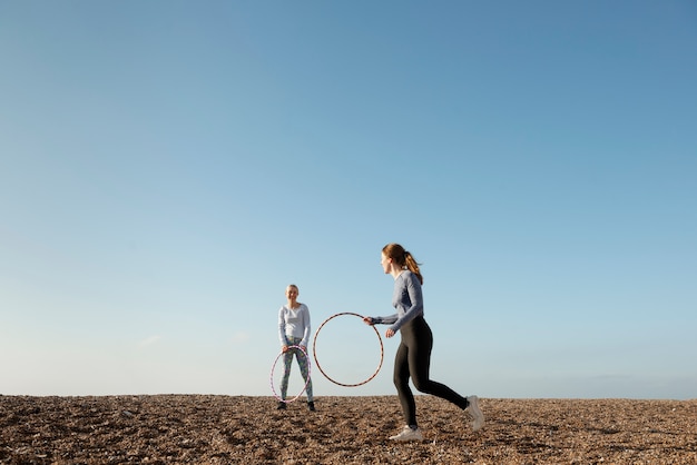 Foto gratuita mujeres haciendo ejercicio con círculo de hula hoop