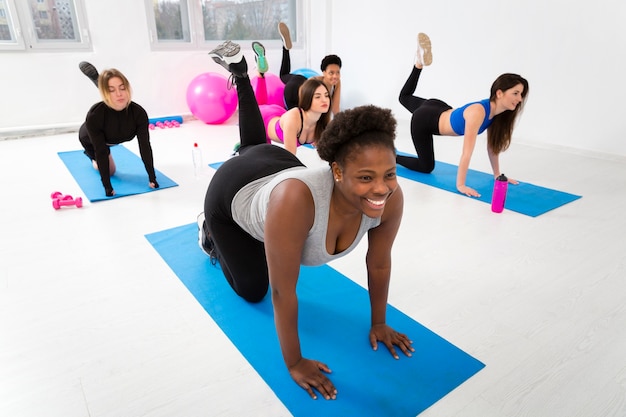 Mujeres haciendo ejercicio en la colchoneta en el gimnasio