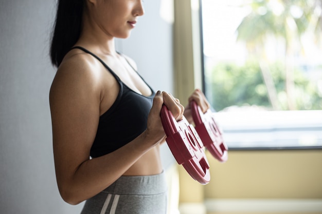 Mujeres haciendo ejercicio con dos pesas con mancuernas