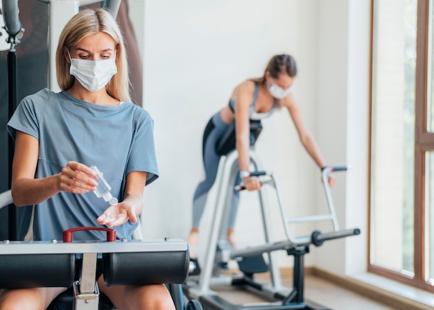 Mujeres haciendo ejercicio en el gimnasio con máscara médica