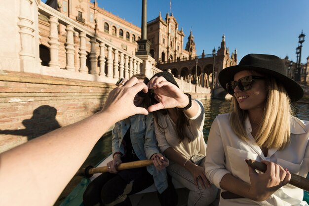 Mujeres haciendo gesto de corazón de mano en barco