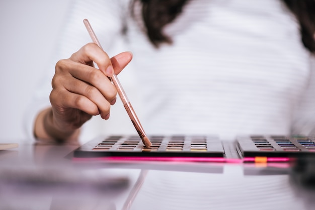 Mujeres haciendo maquillaje con cepillo y cosmetica.