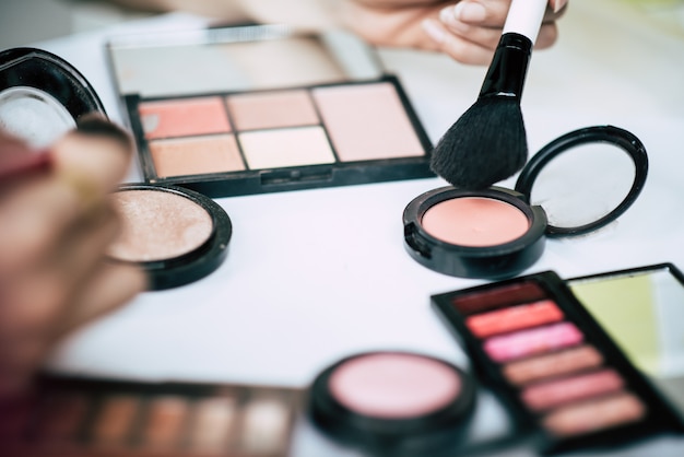 Mujeres haciendo maquillaje con cepillo y cosmetica.